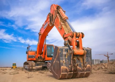 A large orange excavator working on a construction site under a blue sky.